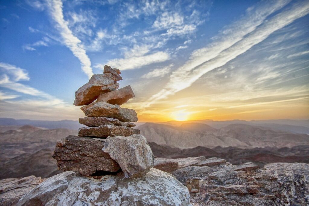 aufgehäufter Steine auf Berggipfel vor Sonnenaufgang